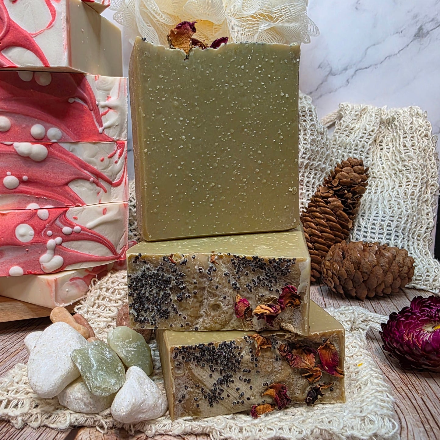 Three handmade soap bars with natural ingredients on a wooden surface with decorative elements.
