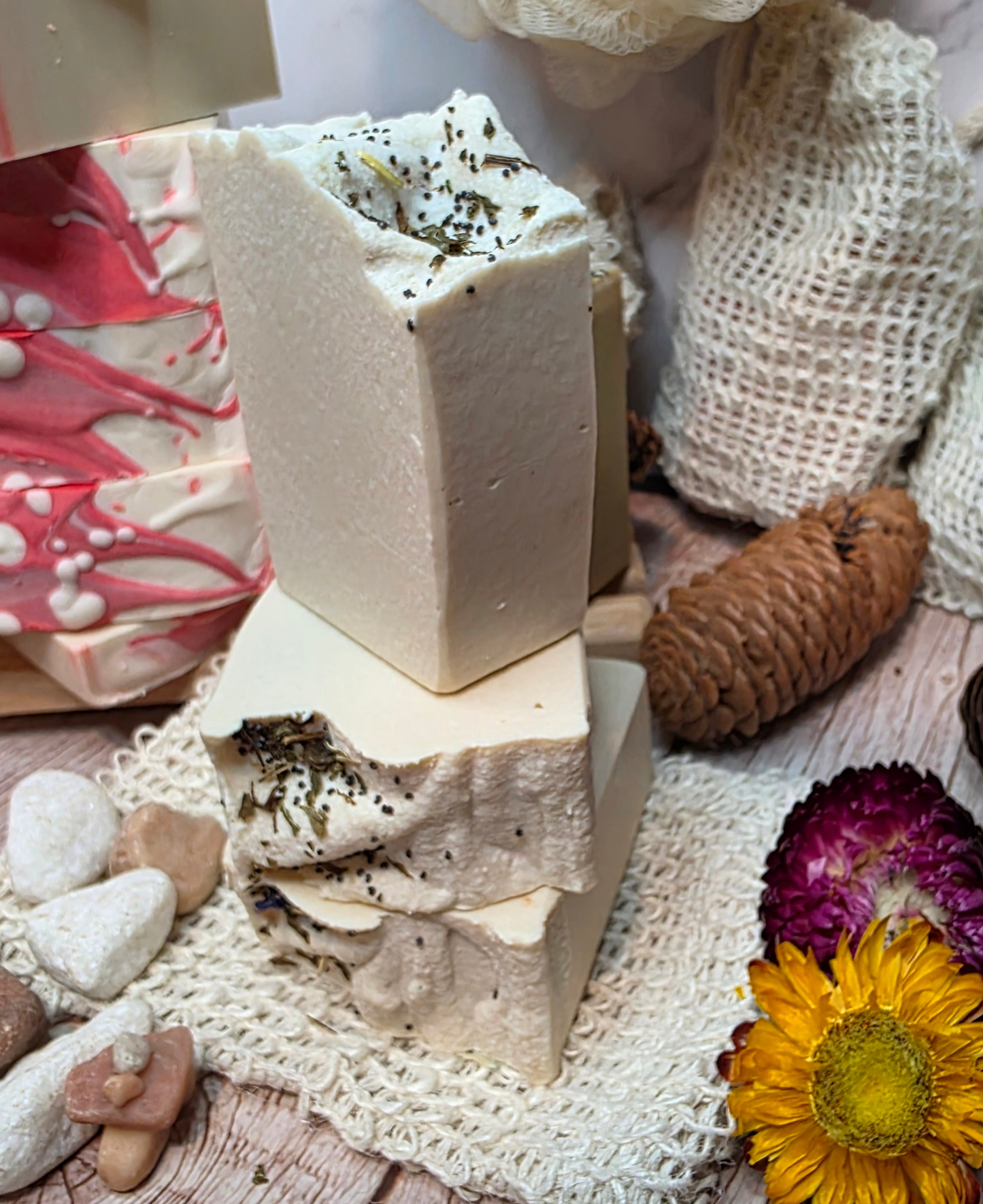 Stack of handmade soap bars with natural elements on a wooden surface