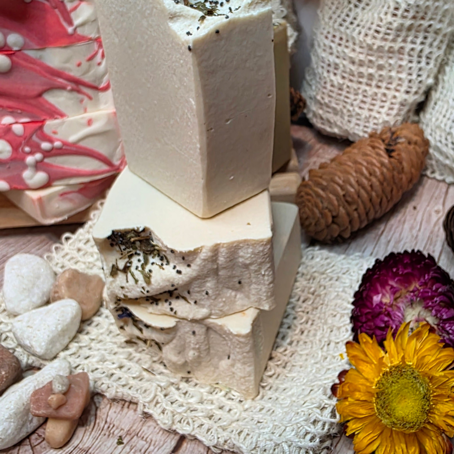Stack of handmade soap bars with natural elements on a wooden surface