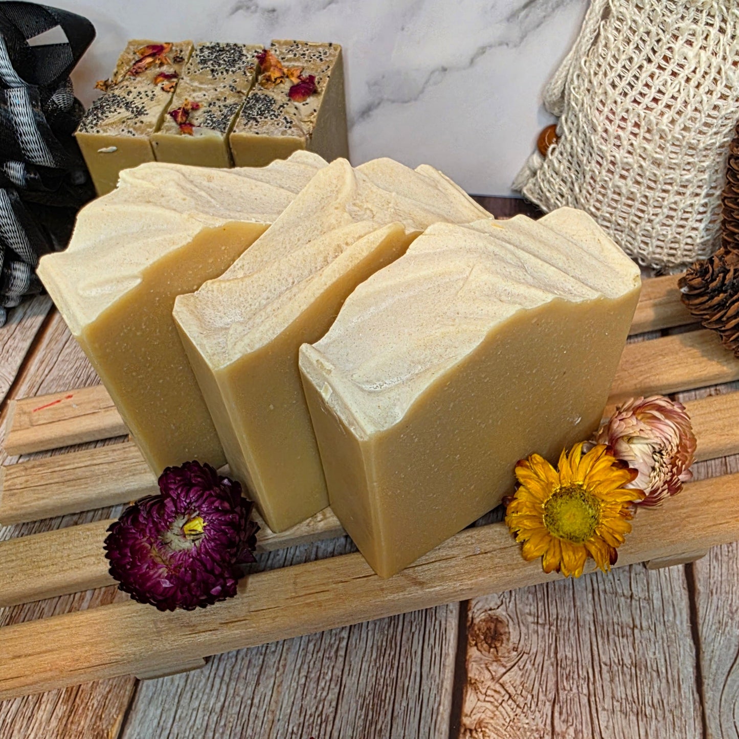 Three bars of soap on a wooden stand with decorative flowers on a rustic wooden surface.