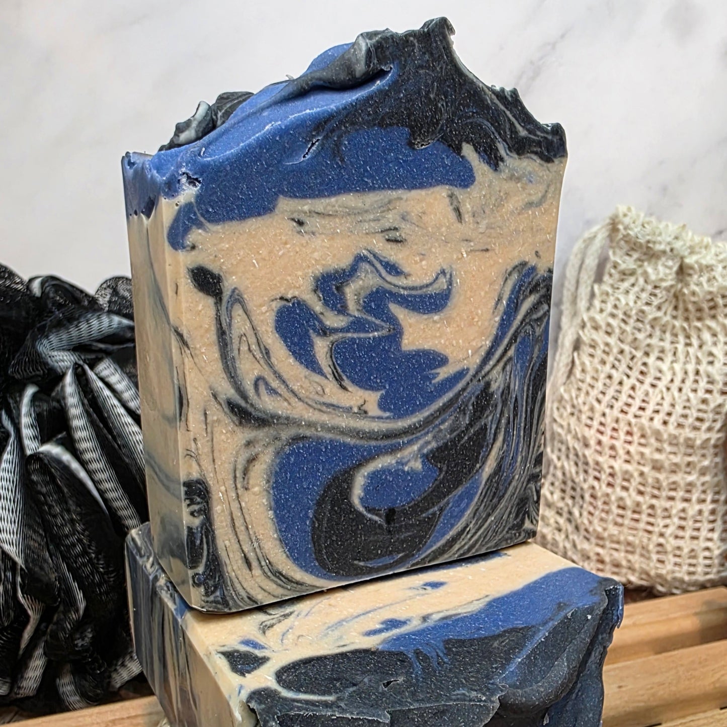 Two bars of soap with blue and black swirls on a wooden surface.