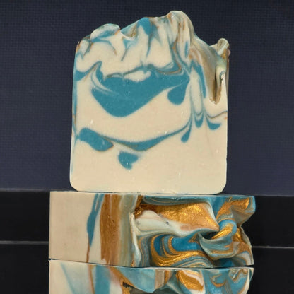 Three marbled soap bars in beige, blue, and gold on a dark background