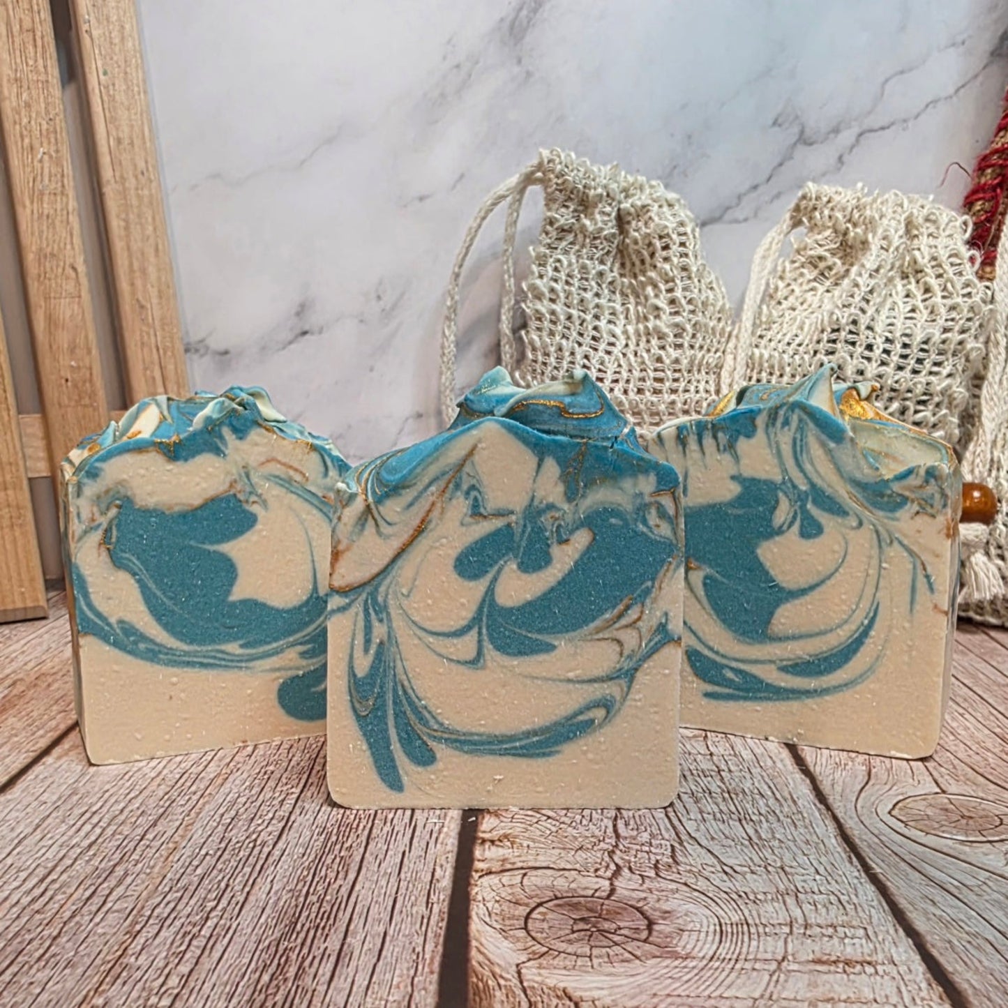 Three marbled soap bars with blue and beige swirls on a wooden surface.