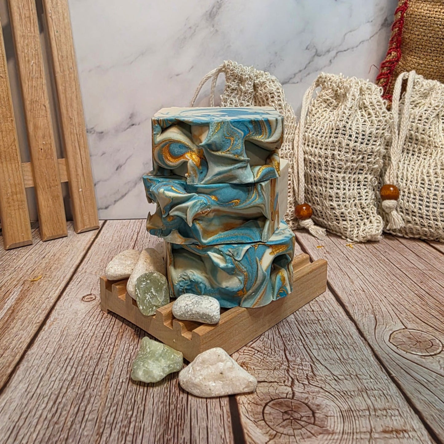 Stack of marbled soap bars on a wooden stand with stones and bags in the background