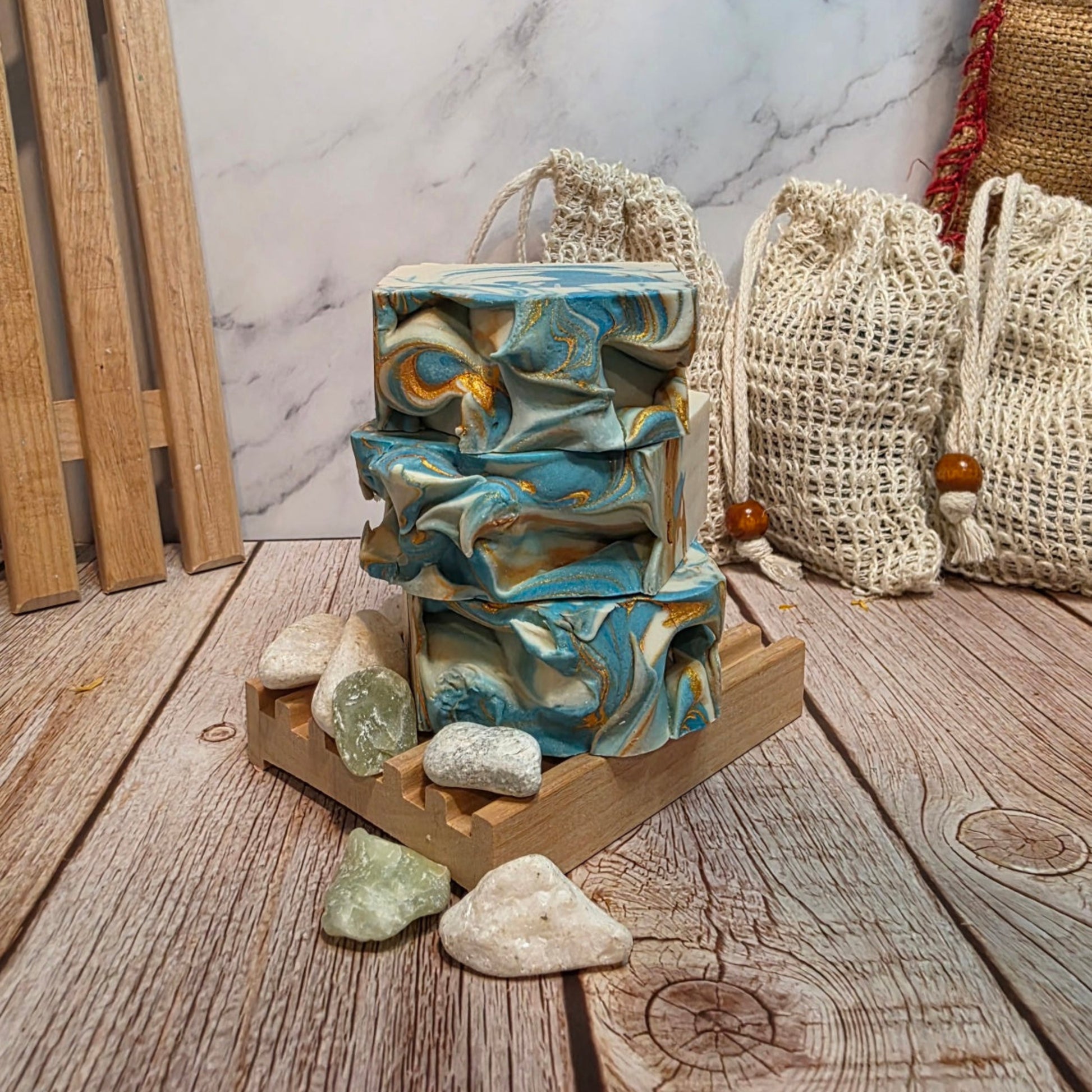 Stack of marbled soap bars on a wooden stand with stones and bags in the background
