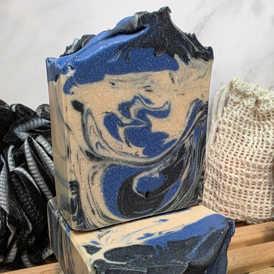 Two bars of soap with blue and black swirls on a wooden surface.