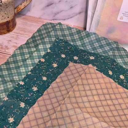 100% cotton beeswax wrap with green floral border on a marble surface
